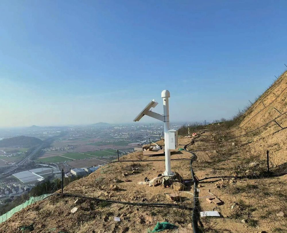 GNSS monitoring station installed on a slope, overlooking the valley